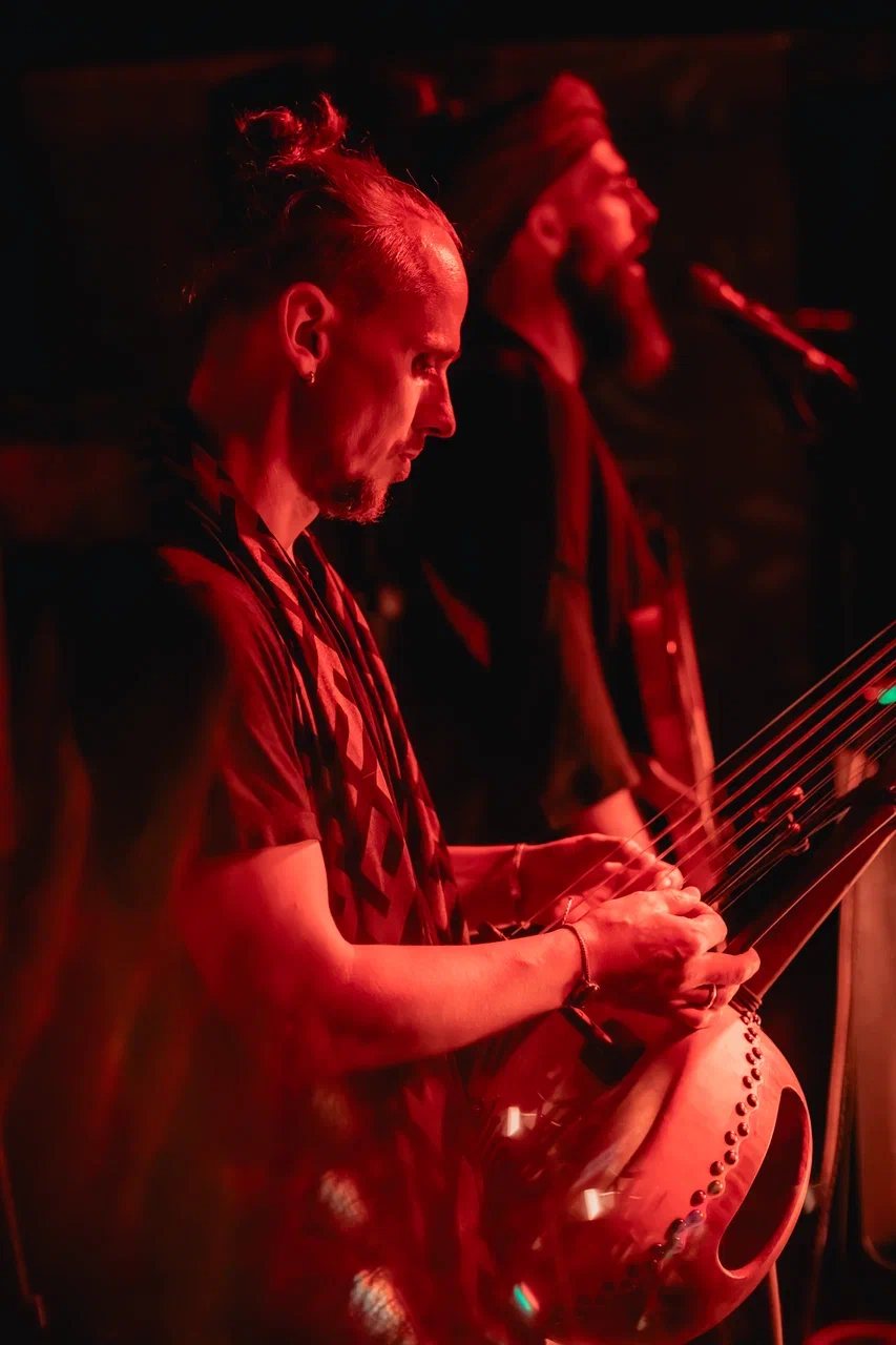 Acharya playing kora in red stage light
